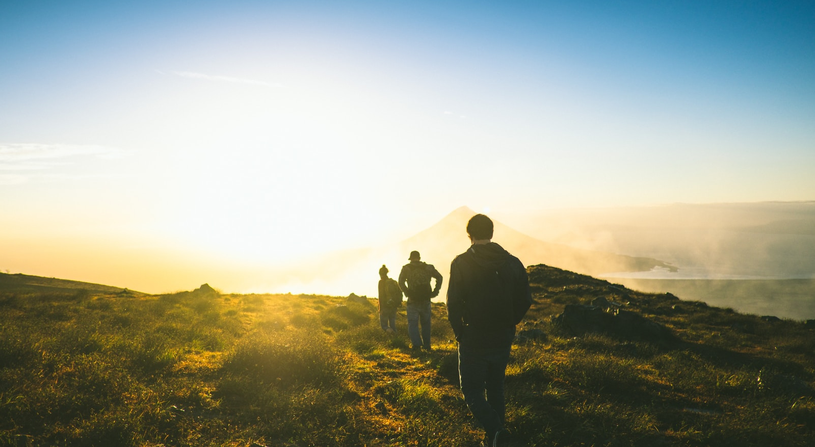 experience silhouette of three men falling in line while walking during golden hour